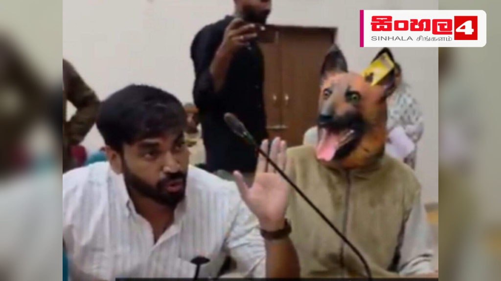 Headline: සුනඛ වෙස්මුහුණක් පැළඳ පැමිණි පුද්ගලයෙකුගෙන් මහ නගර සභාවට බරපතළ චෝදනා Intended image subject: A man wearing a dog mask at a government office protest in Khandwa Story summ
